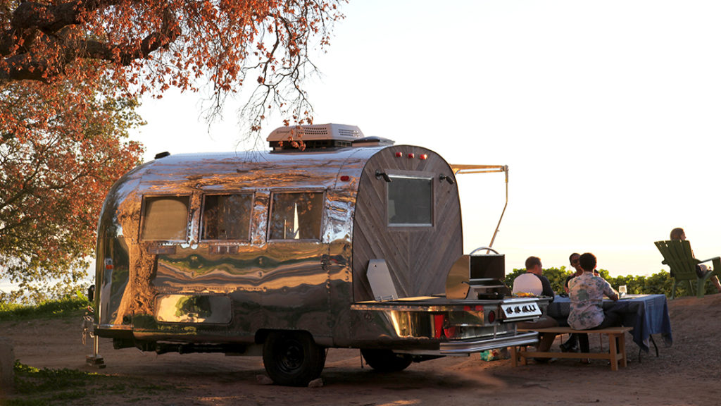 People are eating food near the Airstream Globetrotter